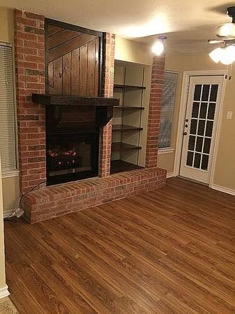 Living area at Emerald Cove with a brick fireplace, wood mantel, built-in shelving and wood-look flooring